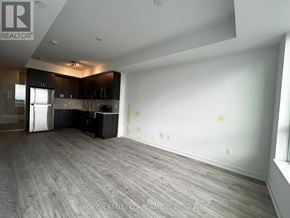 Pickering (Bay Ridges) condo for rent - A large empty room with a kitchen area in the background.