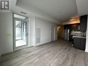 Pickering (Bay Ridges) condo for rent - A spacious, empty room with a kitchen area to the right.