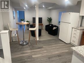 Norfolk multi-family for rent - A well-lit kitchen area with a refrigerator, a dining table with chairs, and a black sofa.