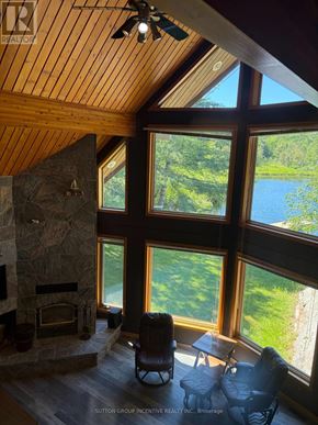 Gravenhurst (Wood (Gravenhurst)) apartment for rent - A living room with a stone fireplace and a view of a lake.