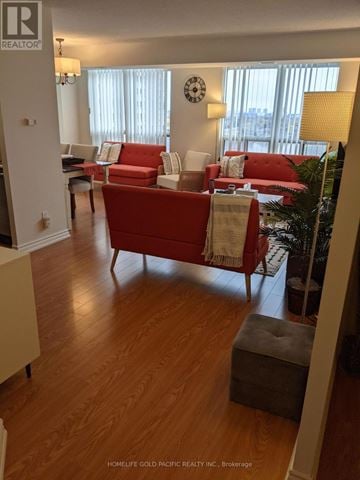 Toronto (Willowdale East) condo for rent - A living room with a red couch and a wooden floor.