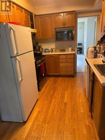 Barrie (West Bayfield) apartment for rent - A kitchen with a white refrigerator and wooden cabinets.