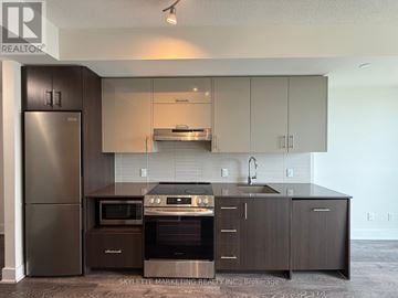 Toronto (Don Valley Village) condo for rent - A modern kitchen with dark wood cabinets and stainless steel appliances.