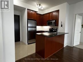 Mississauga (City Centre) condo for rent - A kitchen with brown cabinets and black appliances.