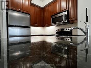 Mississauga (City Centre) condo for rent - A kitchen with a refrigerator, microwave, and stove top oven.