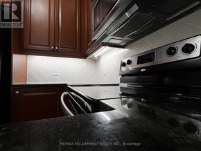Mississauga (City Centre) condo for rent - A kitchen with a black stove top oven and brown cabinets.