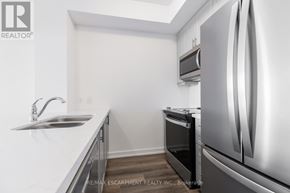 Hamilton (Waterdown) condo for rent - A modern kitchen with a stainless steel refrigerator and a sink with a faucet.