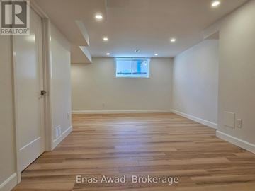 Ottawa apartment for rent - A spacious room with wooden flooring and white walls.