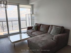 Toronto (University) condo for rent - A grey couch with a glass table in front of a window with a view of the city.
