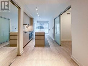 Toronto (Waterfront Communities) condo for rent - A spacious hallway with wooden floors and glass doors leading to a kitchen area.