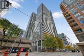 Toronto (Bay Street Corridor) condo for rent - A tall building with a glass facade stands in front of a parking garage.