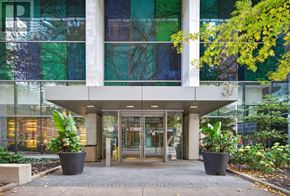 Toronto (Bay Street Corridor) condo for rent - The front of a building with glass windows and doors, with two large potted plants on either side of the entrance.