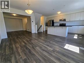 Cambridge townhouse for rent - A large open space with wood flooring and a kitchen area with white cabinets.