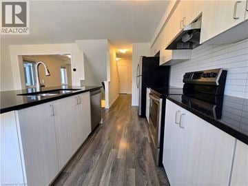 Cambridge townhouse for rent - A modern kitchen with white cabinets and black countertops.
