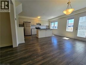 Cambridge townhouse for rent - A well-lit, empty living room with wood flooring and a kitchen area in the background.