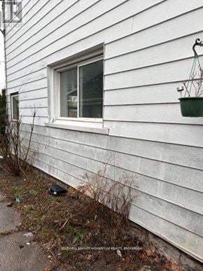Welland (Welland Downtown) triplex for rent - A white house with a window and a plant on the siding.