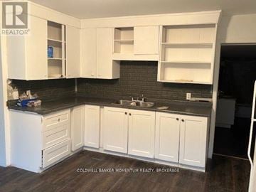 Welland (Welland Downtown) triplex for rent - A kitchen with white cabinets and a black countertop.