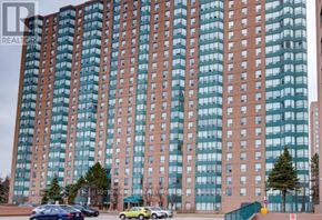 Mississauga (Cooksville) condo for rent - A tall building with many windows and cars parked in front.
