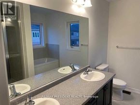 Brantford apartment for rent - A bathroom with a large mirror, two sinks, and a toilet.