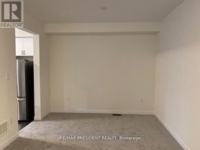 Brantford apartment for rent - A spacious room with a carpeted floor and a refrigerator in the corner.
