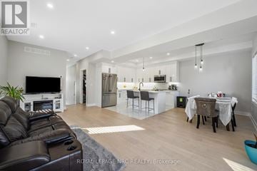 Welland (N. Welland) apartment for rent - A well-lit, modern living room with a black leather sofa and a kitchen area in the background.