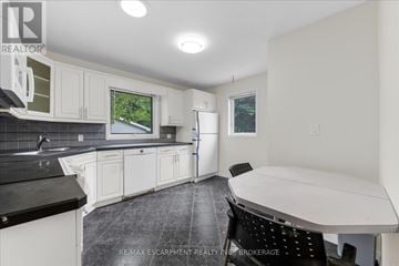 St. Catharines (Fairview) apartment for rent - A kitchen with white cabinets and black countertops.