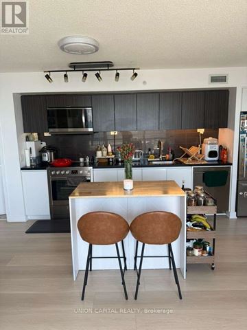 Toronto (Waterfront Communities) condo for rent - A kitchen with a table and two chairs in the middle.