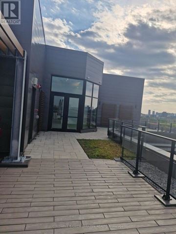 Ottawa condo for rent - The image shows a modern building entrance with glass doors and a brick walkway leading to it.