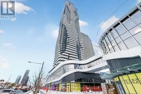 Vaughan (Vaughan Corporate Centre) condo for rent - A tall building with a curved glass facade stands next to a smaller building with a flat glass facade.
