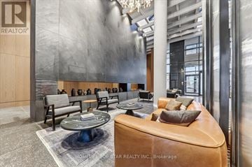 Vaughan (Vaughan Corporate Centre) condo for rent - A modern living room with a brown leather sofa and a grey coffee table.