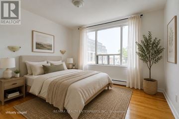 Toronto (South Riverdale) triplex for rent - A bedroom with a large bed and a view of the city.