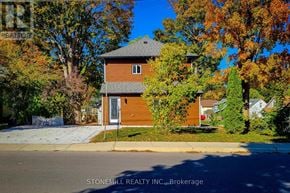 Woodstock (Woodstock - South) apartment for rent - A house with a brown roof and a white door is surrounded by trees with orange leaves.
