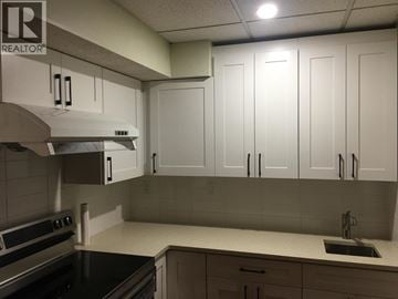 Coquitlam apartment for rent - A kitchen with white cabinets and a black countertop.
