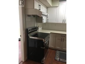 Coquitlam apartment for rent - A kitchen with a black dishwasher and white cabinets.