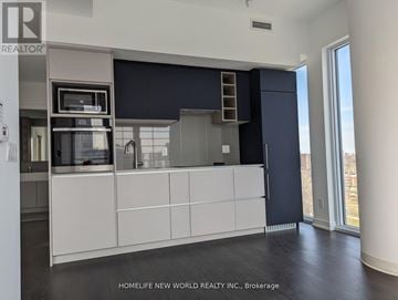 Toronto (Church-Yonge Corridor) condo for rent - A modern kitchen with white cabinets and a black backsplash.