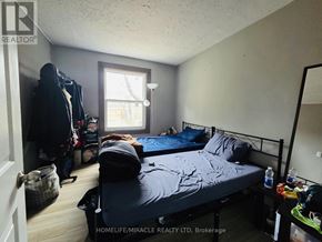 Windsor apartment for rent - A bedroom with a bed, a window, and a clothing rack.