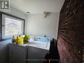 Windsor apartment for rent - A laundry room with a washer and dryer, a window, and a brick wall.
