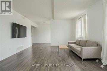 Barrie (Holly) condo for rent - A living room with a couch, a television, and a window.