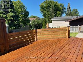 Quinte West (Trenton Ward) apartment for rent - A wooden deck with a fence and trees in the background.