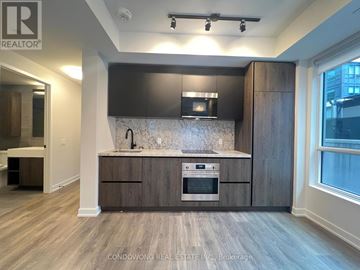 Toronto (Waterfront Communities) condo for rent - A modern kitchen with dark wood cabinets and a marble backsplash.