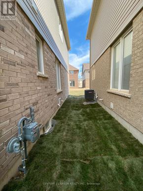 Brantford apartment for rent - A grassy area between two brick buildings with a mailbox in the middle.