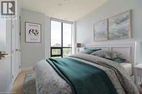 Hamilton condo for rent - A bedroom with a bed covered in a green comforter and a painting on the wall.