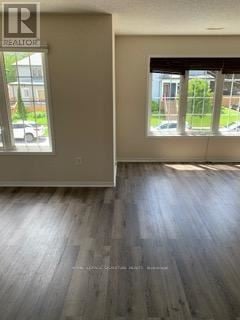 Oshawa (Vanier) multi-family for rent - A room with a wooden floor and a window showing a parking lot outside.