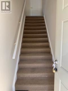 Oshawa (Vanier) multi-family for rent - A staircase with a carpeted runner and a white door at the bottom.