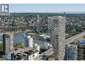 Vancouver apartment for rent - A cityscape with a tall building in the foreground and a body of water in the middle ground.
