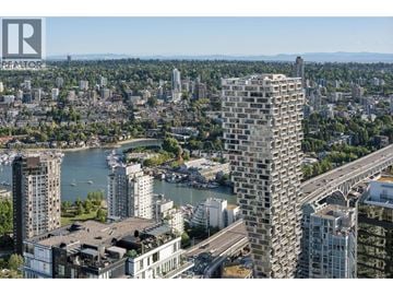 Vancouver apartment for rent - A cityscape with a tall building in the foreground and a body of water in the middle ground.