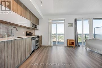 Toronto (Mimico) condo for rent - A modern kitchen with wooden cabinets and a large window overlooking the ocean.