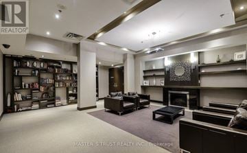 Mississauga (City Centre) condo for rent - A living room with a fireplace and a bookshelf filled with books.