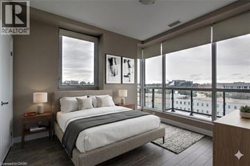Kitchener condo for rent - A bedroom with a large bed and a view of the city.
