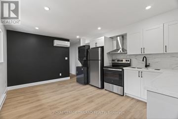 London South (South J) multi-family for rent - A modern kitchen with white cabinets and a black wall.